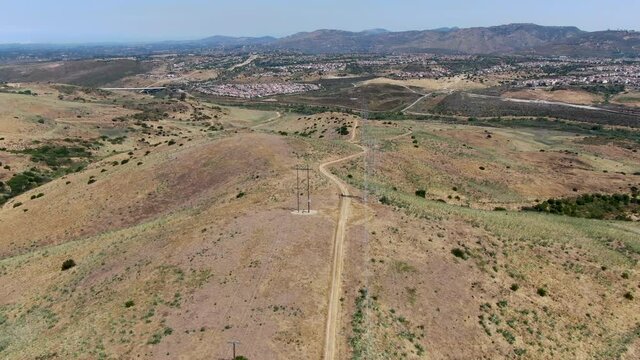 Aerial view of electricity transmission pylon in dry valley landscape. High voltage electricity distribution, California