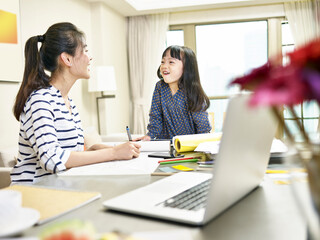 asian mother working at home while caring for daughter
