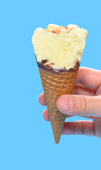 hand holding a fresh pineapple ice cream cone with couple of bites on blue background