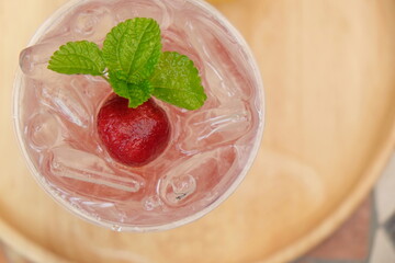 Close-up strawberry with mint on ice drink with blurred background, drink of minerals water with fresh strawberry and mint, ice fresh drink cocktail at traveling trip, beverage of summer concept