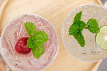 Close-up strawberry with mint on ice drink with blurred background, drink of minerals water with fresh strawberry and mint, ice fresh drink cocktail at traveling trip, beverage of summer concept