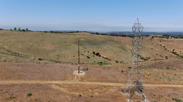 Aerial view of electricity transmission pylon in dry valley landscape. High voltage electricity distribution, California