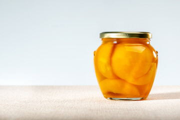 Canned peaches in glass jar on the table. Copy space.
