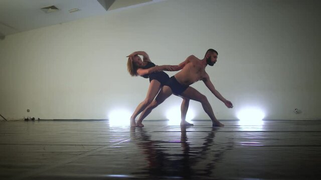Couple of modern dancers performing different moves ini studio