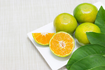Tangerine is both fruit and split in a white dish background cloth.
