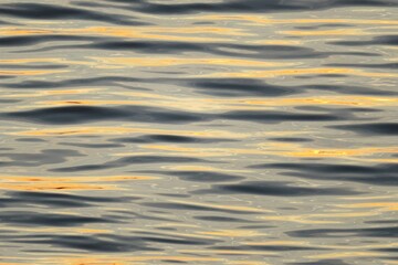 Naklejka na ściany i meble Water surface with yellow sun glare on the waves, natural background