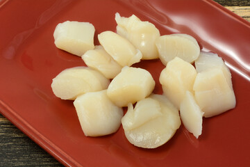 Raw uncooked scallops seafood on red plate in preparation for grilling or cooking