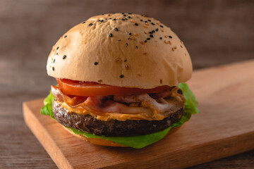 hamburguesa de carne de entraña argentina, con tomate, queso, bacon y lechuga en primer plano con foco selectivo sobre un fondo de madera