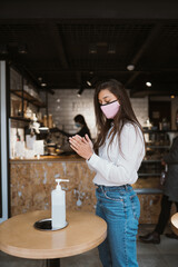 Woman using sanitizer gel cleans hands of coronavirus virus at cafe.