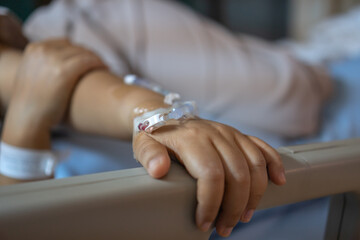 Virus Treatment of Patients saline, Iv drip, young woman hand with medical drip intravenous needle on hospital bed. intravenous therapy (IV) is a therapy that delivers fluids directly into vein