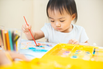 Cute asian little girl is painting the color with fully happiness moment , concept of art and education for kid. closed up kid practice paiting for homeschooling.Lovely asian girl drawing