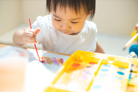 Cute asian little girl is painting the color with fully happiness moment , concept of art and education for kid. closed up kid practice paiting for homeschooling.Lovely asian girl drawing