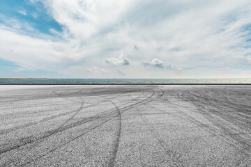 Empty asphalt road and lake under blue sky.