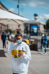 Young woman holding coffee wearing protective medical mask