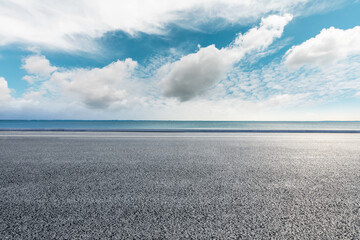 Empty asphalt road and lake under blue sky.