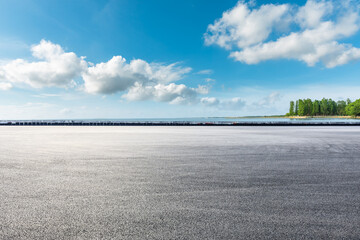 Empty asphalt road and lake under blue sky.