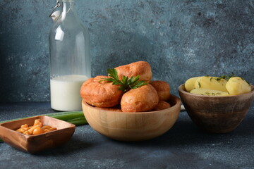 Tasty breakfast rustic style. Stuffed Buns (Pirozhki) ,milk,with green onions and Homemade pickled honey agarics mushrooms,and potatoes. Flowers at background