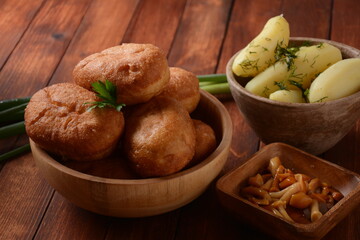Stuffed Buns (Pirozhki) in wooden bowl on the wooden background. With green onions ,and herbs. Homemade pasty, Russian stuffed pastry.