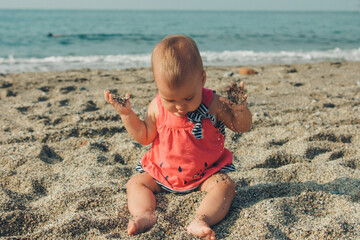 a small child plays in the sand. girl sitting on the beach