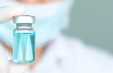 Doctor's hand holds a syringe and a blue vaccine covid19 bottle at the hospital. Health and medical...