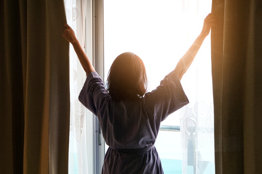 Morning of a new day, alarm clock wake up man sitting in the room. A woman stretch the muscles at window. Health and care concepts
