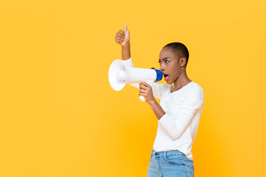 African American Woman Shouting On Megaphone And Giving Thumbs Up Isolated On Yellow Background