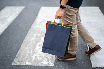 man holding shopping bag walking cross the street