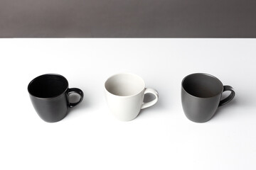 Three black, grey and white isolated tea cups on the table. Horizontal table and construction lines. Copy space for editing. Modern monochrome wallpaper 