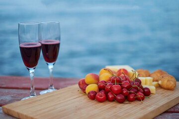 Two glasses of red wine, served outdoor with fruits and beautiful blue ocean view.
