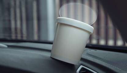 Closeup ice cream paper cup container inside a car.