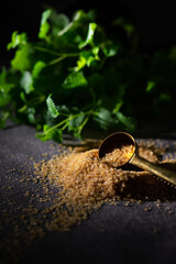 Brown sugar with gold color spoon and a twig of mint (Mentha).  Copy space for text. Black background