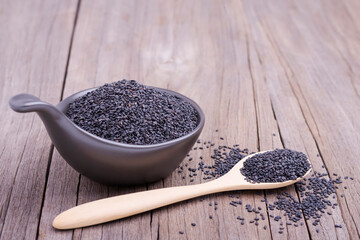 Sesame seeds in a wooden spoon and in a cup And with sesame seeds scattered on the wooden table
