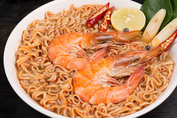 Instant noodles, spicy hot and spicy shrimp soup with Thai spices put on the table in the kitchen, black background