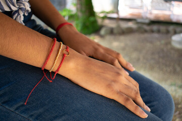 woman's hand with red and gold bracelet on jean pants