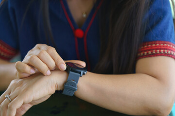 An Asian woman adjust or check her smart watch