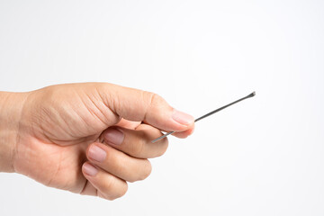 Hand holding steel ear pick for cleaning
