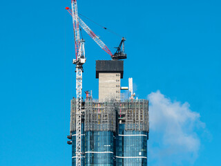 Construction site of modern multi-level building with a clear blue sky. Workers operating...