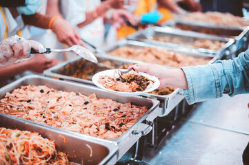 The hands of the poor receive food that volunteers share to alleviate hunger: the concept of donating food to the poor