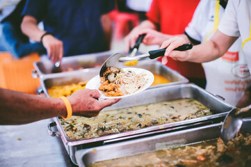 The hands of the poor receive food that volunteers share to alleviate hunger: the concept of...