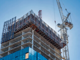 Building and construction scene. Heavy machinery lifting up materials. Blue sky, real estate development. - obrazy, fototapety, plakaty