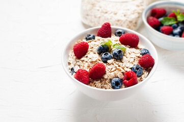 Breakfast, oatmeal with blueberry and raspberry on white bowl in the morning.