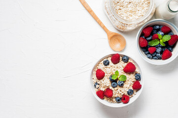 Breakfast, oatmeal with blueberry and raspberry on white bowl in the morning.