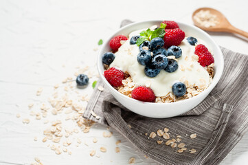 Breakfast, oatmeal with blueberry and raspberry on white bowl in the morning.