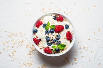 Breakfast, oatmeal with blueberry and raspberry on white bowl in the morning.