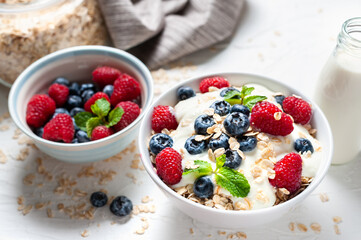 Breakfast, oatmeal with blueberry and raspberry on white bowl in the morning.