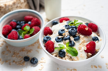 Breakfast, oatmeal with blueberry and raspberry on white bowl in the morning.