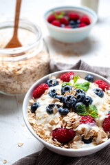Breakfast, oatmeal with blueberry and raspberry on white bowl in the morning.