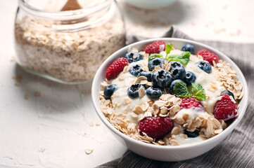 Breakfast, oatmeal with blueberry and raspberry on white bowl in the morning.