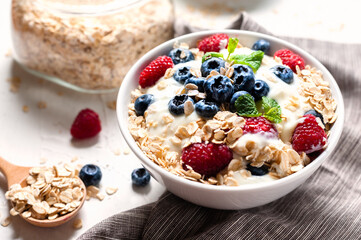 Breakfast, oatmeal with blueberry and raspberry on white bowl in the morning.
