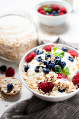 Breakfast, oatmeal with blueberry and raspberry on white bowl in the morning.